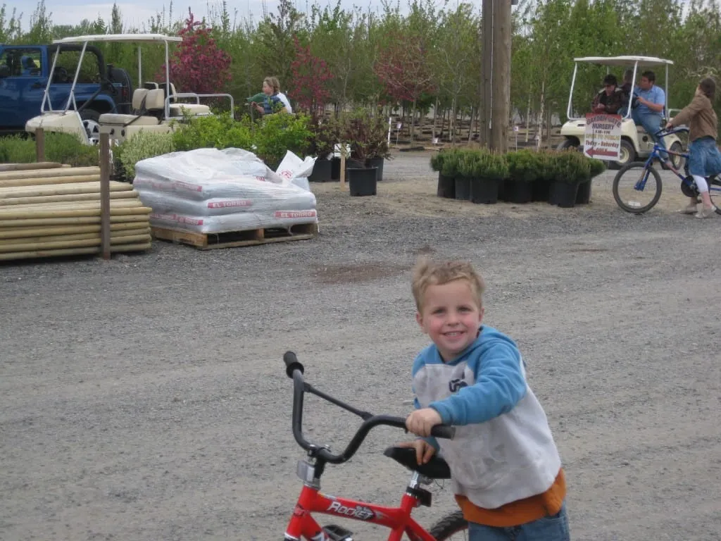 Boy with a red bicycle and a golf cart signed Open to Public at Garden Gate
