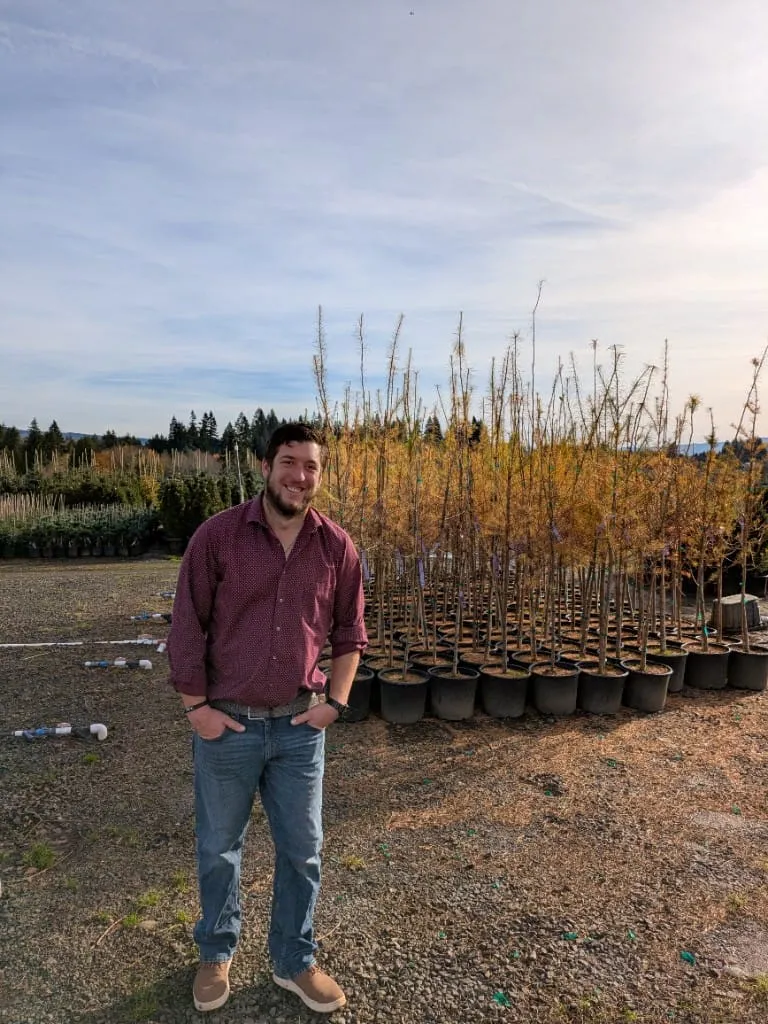 Eric smiling among rows of young trees at the Boring, Oregon nursery